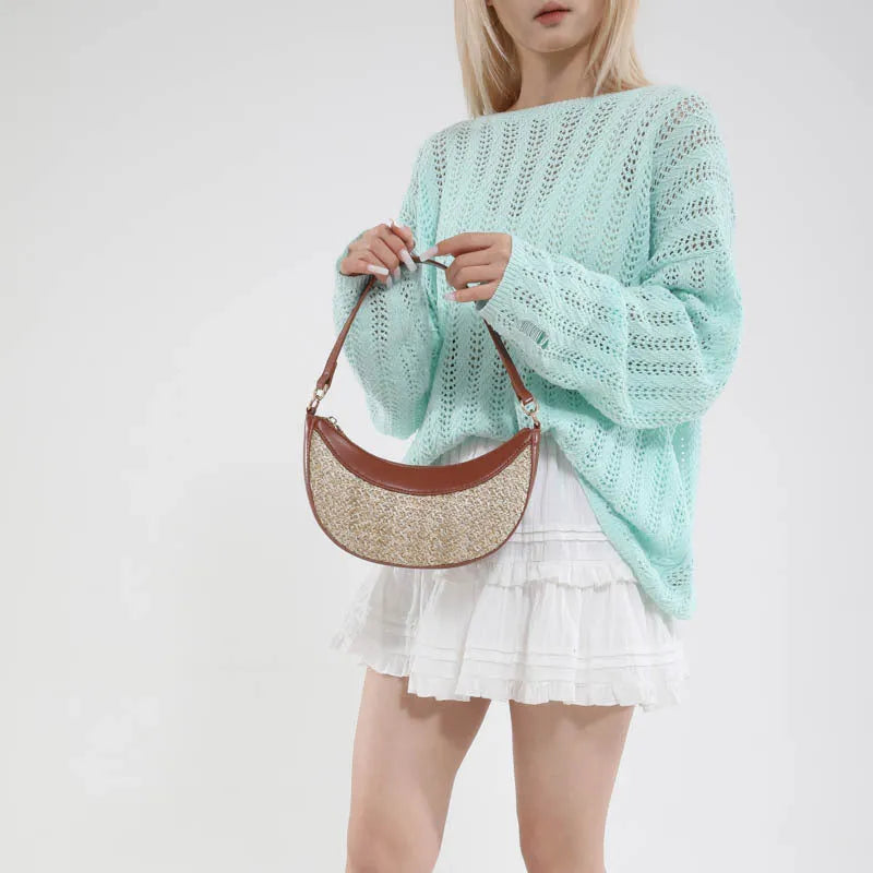 Hard woven straw dumpling-shaped crossbody bag in green with contrast stitching and a single shoulder strap.