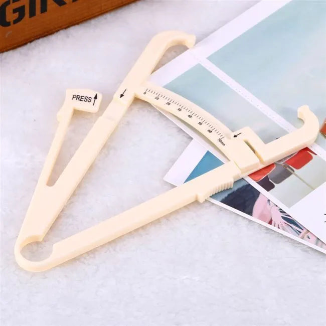 Transparent acrylic body fat caliper with measurement scale on a white background.