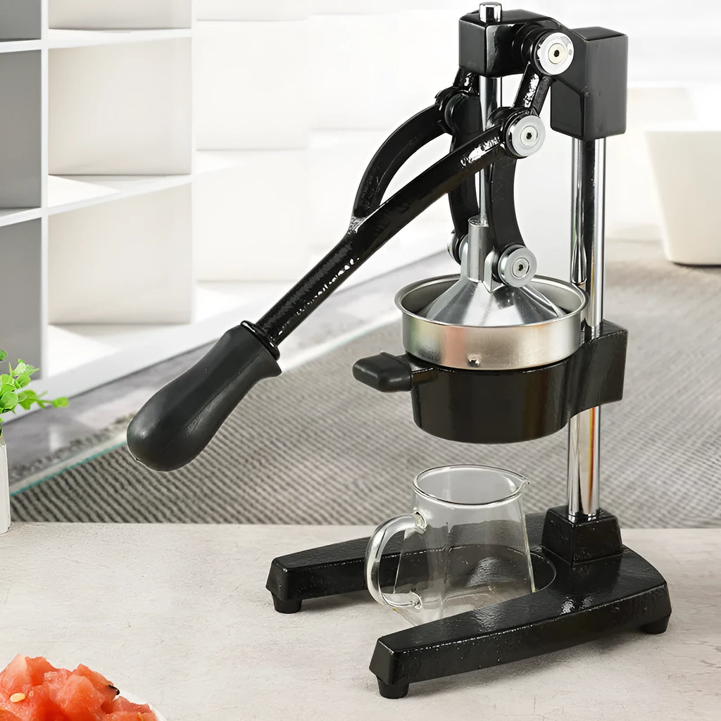 A black cast iron manual citrus juicer with a stainless steel strainer on a kitchen counter.