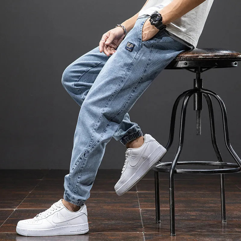 Man wearing loose fit straight leg cargo jeans in blue, showing zipper fly and cargo pocket detail.
