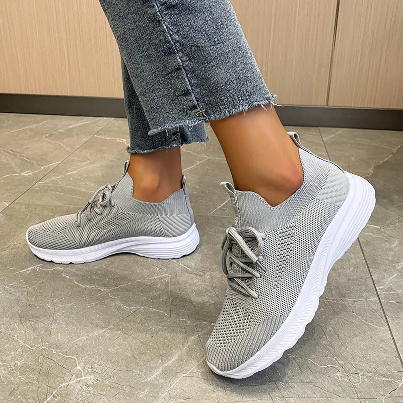 Women's creamy white Flyknit running shoes with mesh lining and low-top design on a rubber sole