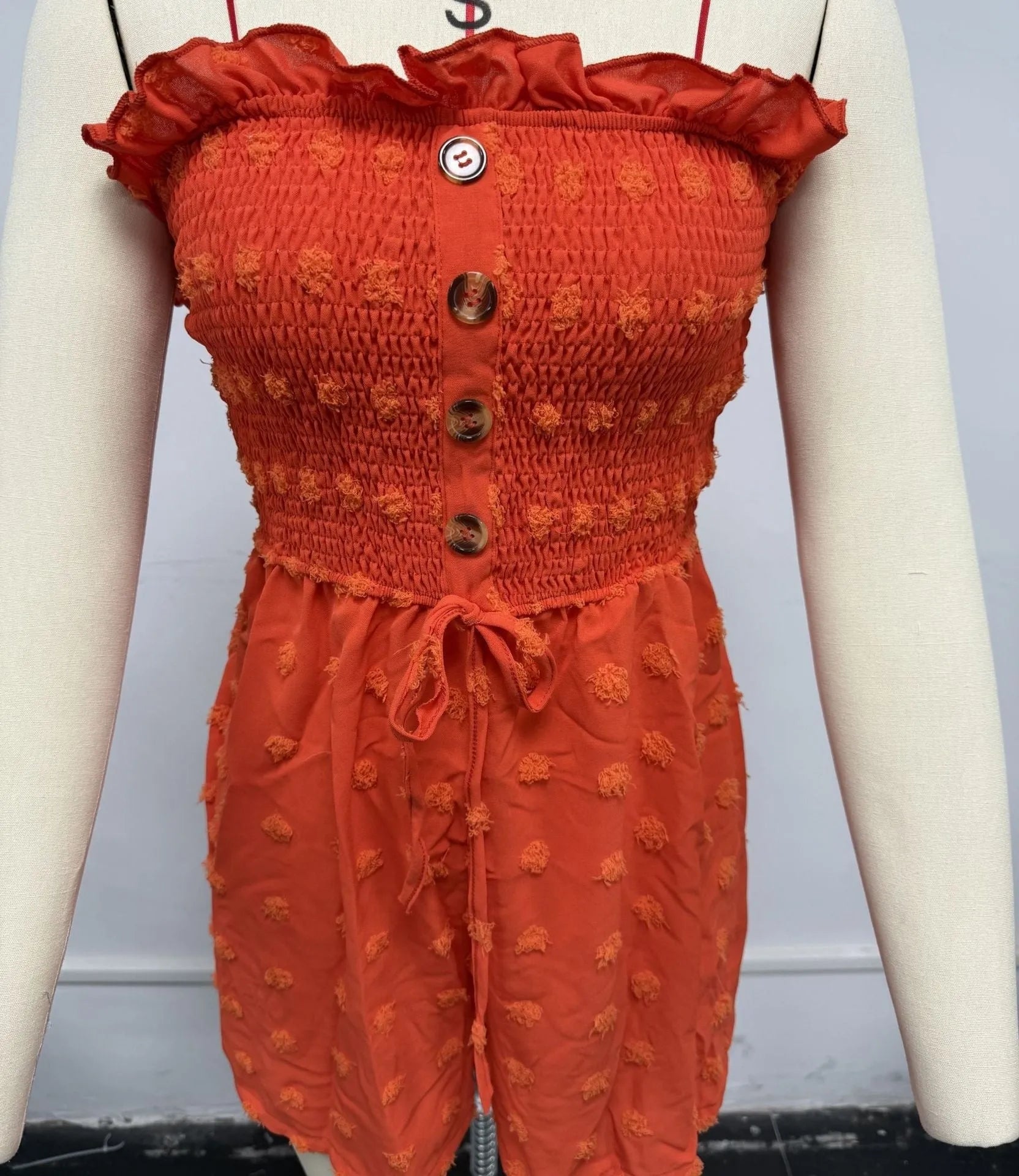 Women's sleeveless off-shoulder jumpsuit in solid colour with elastic waist and button details