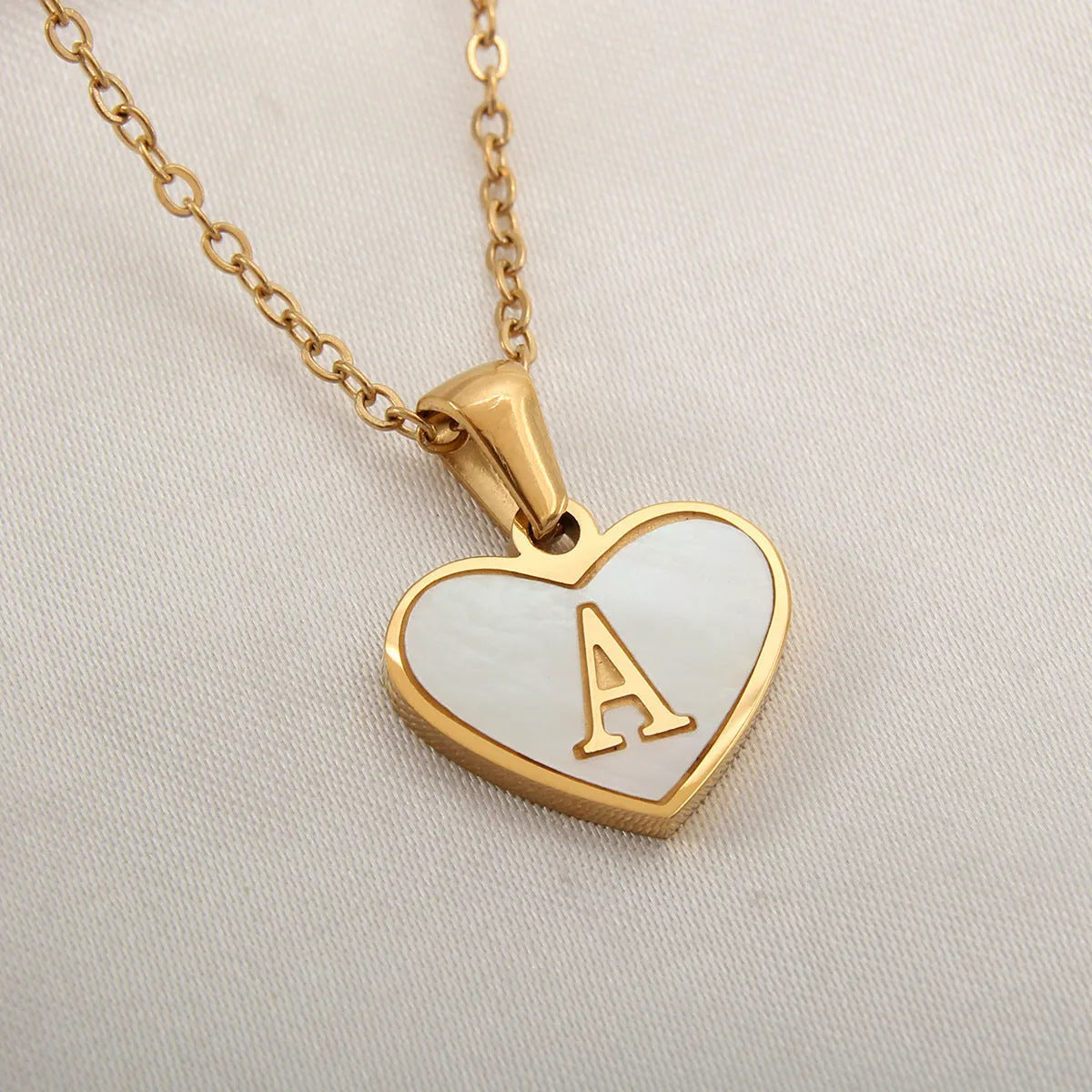 Gold-plated heart necklace with white shell pendant personalised with a letter, on an adjustable chain.