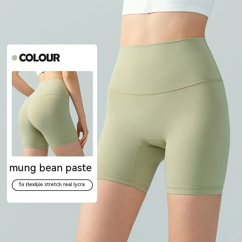 Women's high waist Lycra yoga shorts in leaf green, shown in a yoga pose.