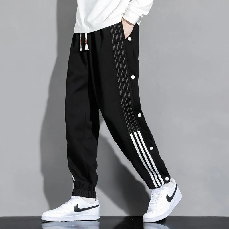 Man wearing loose grey cotton blend sweatpants with ankle ties and a drawstring waist.