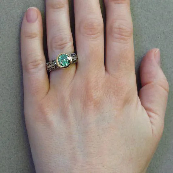 Gold-plated flower-shaped vintage ring with a green gemstone on a model's finger