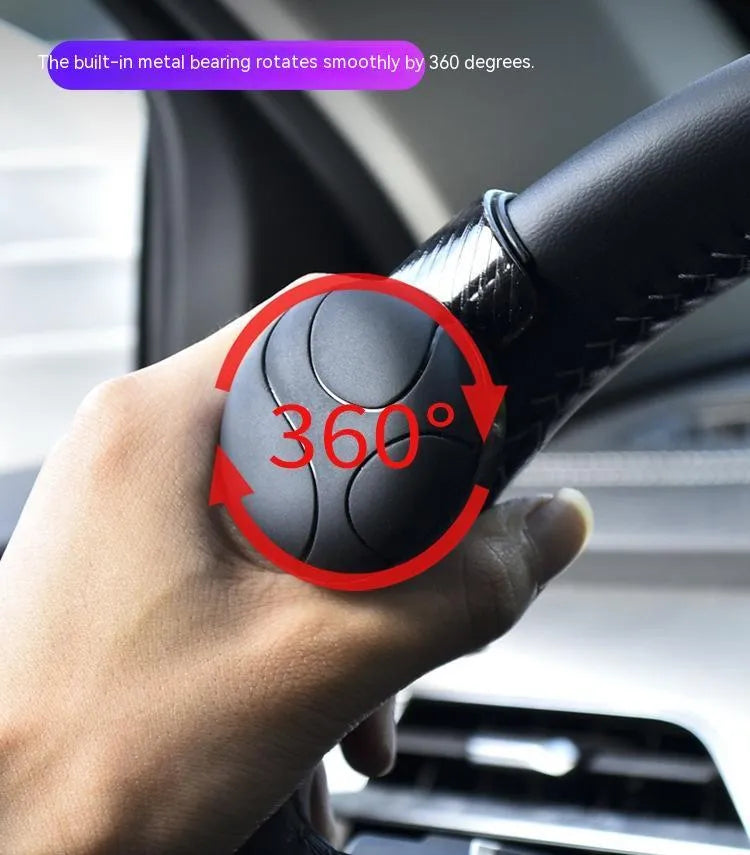 Close-up of black silicone steering wheel assist ball with metal bearing mechanism attached to a car steering wheel rim