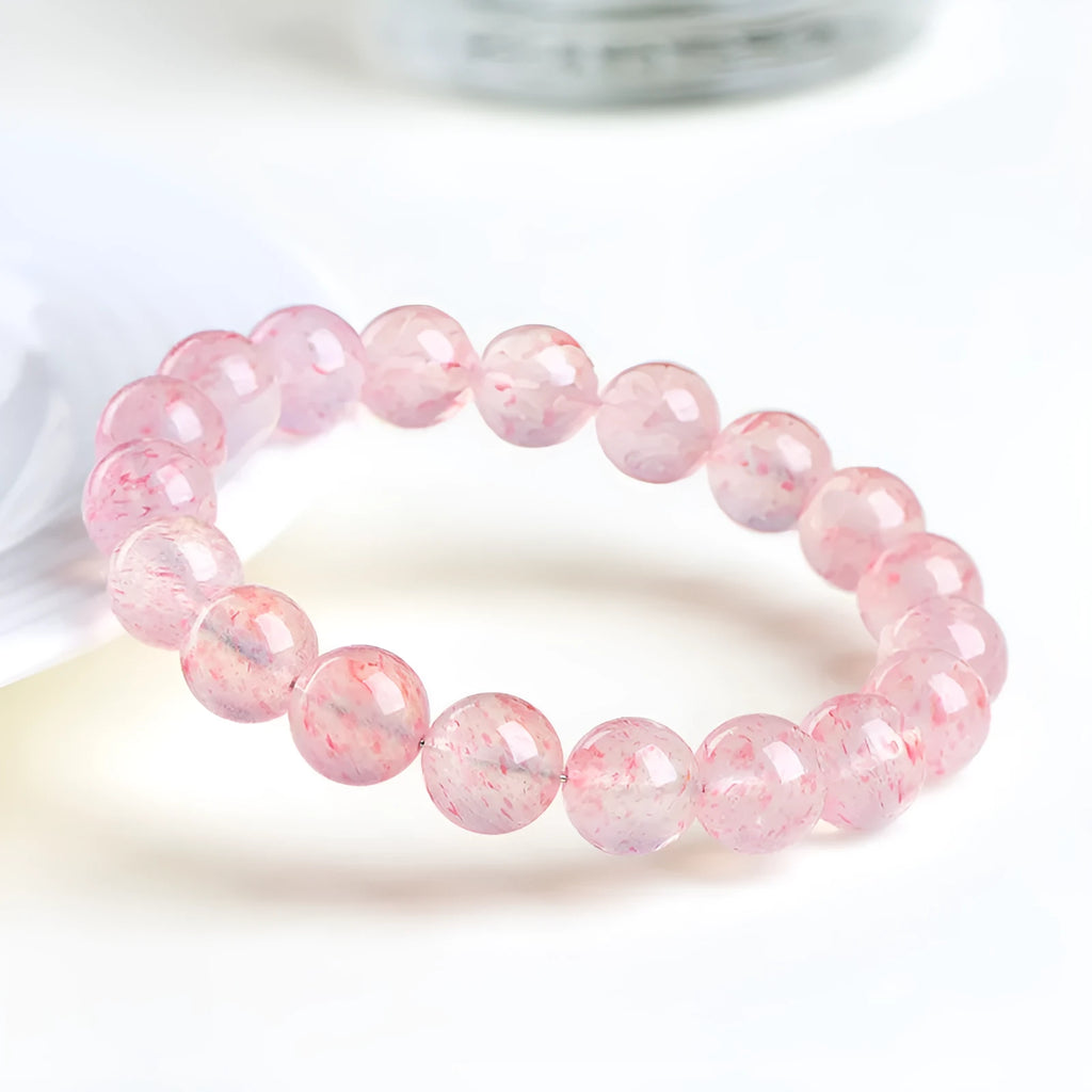 Natural strawberry quartz crystal bracelet with 19 round geometry beads on a white background.