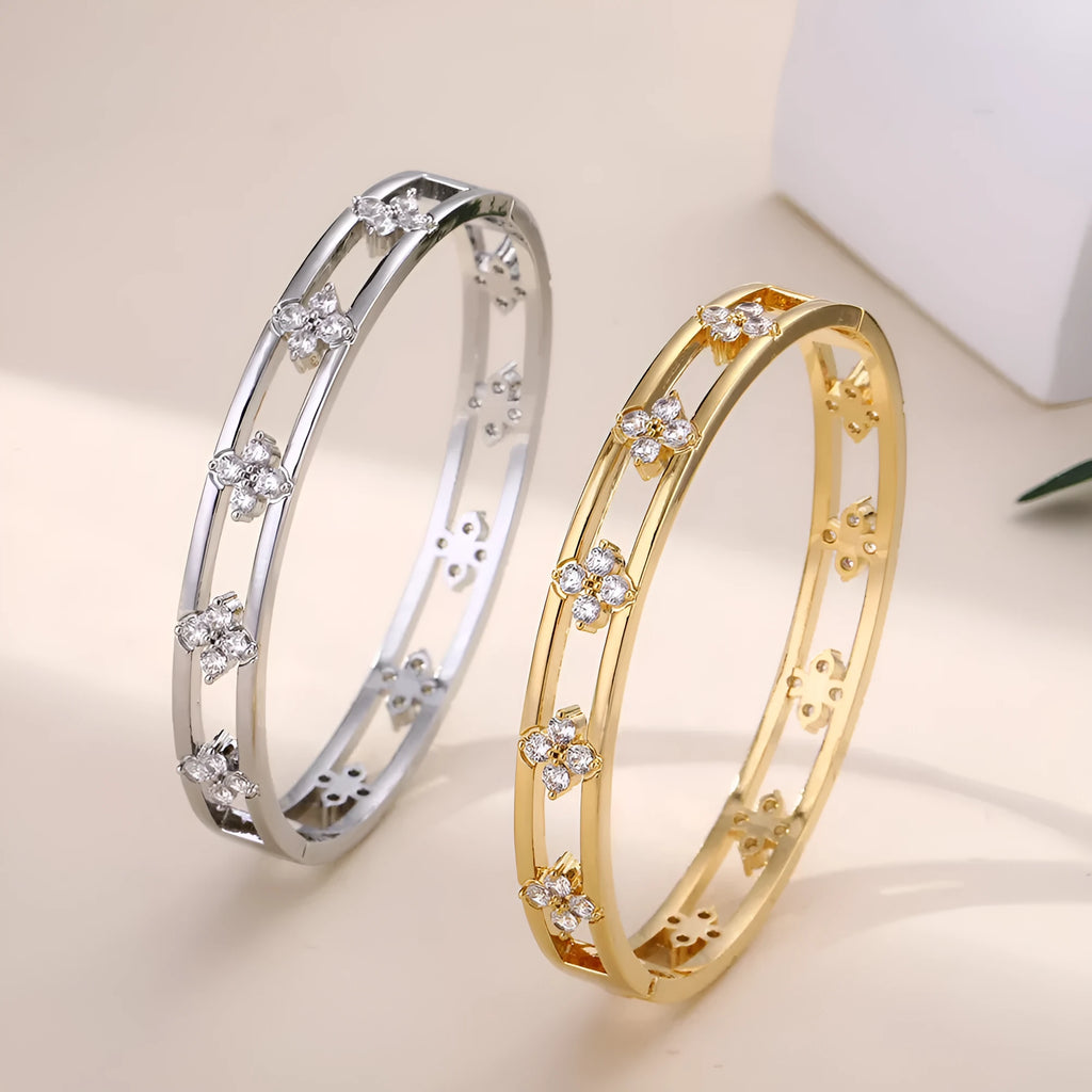 Gold or silver adjustable hollow bracelet with a four-leaf clover charm inlaid with a zircon stone.