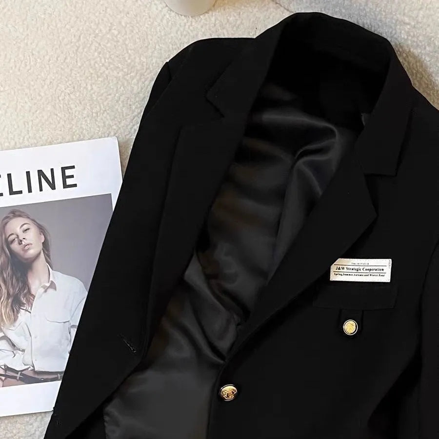 Women's black loose-fit short suit coat with long sleeves and pocket details.
