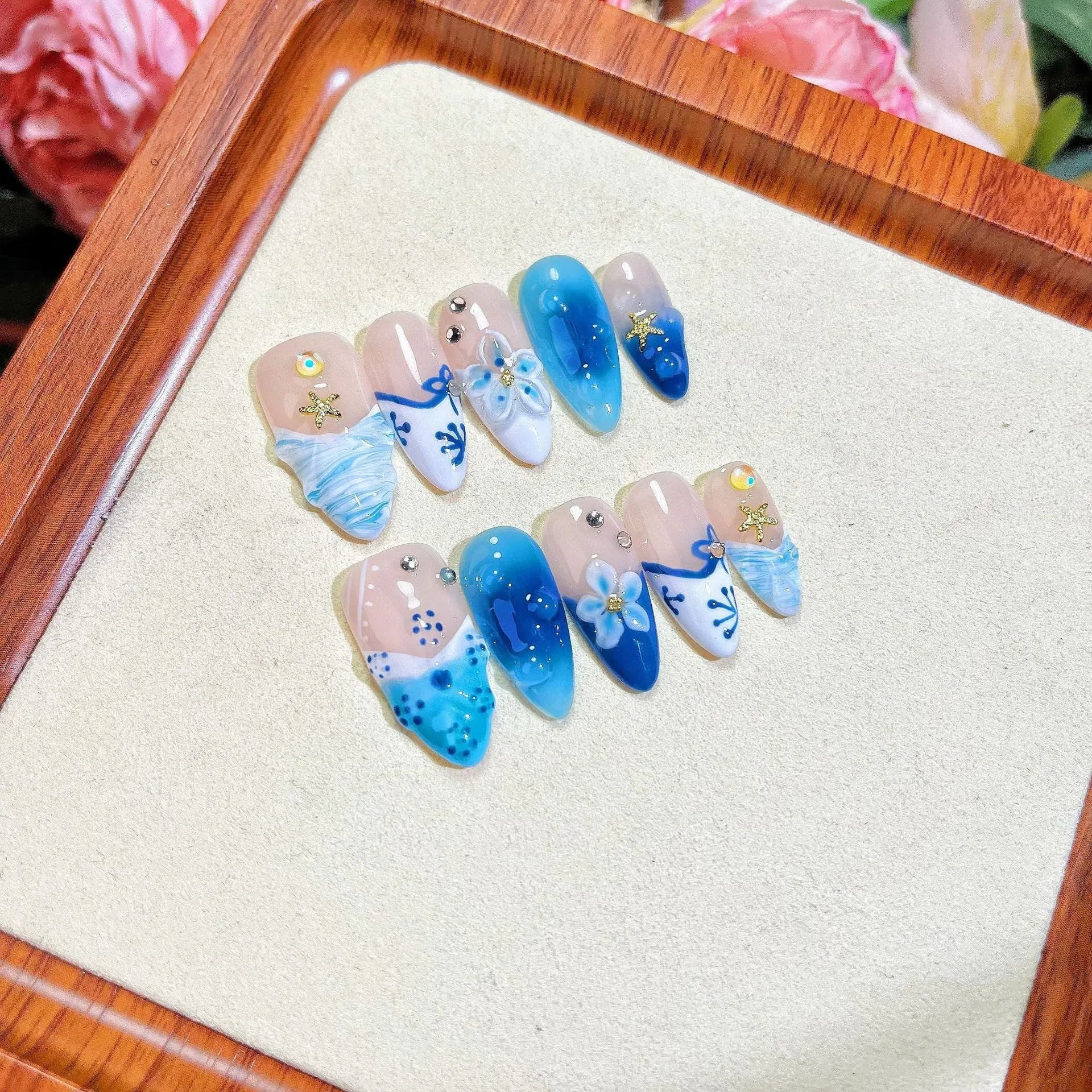 Set of blue carved plastic wearable artificial nails showing hand-painted summer ice design, laid out in sizes XS, S, M, L