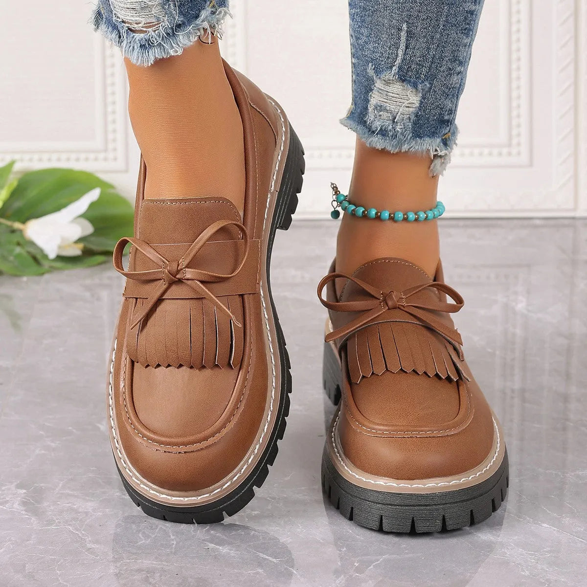 Plus size women's black loafers with a tassel and bow knot detail on the upper.