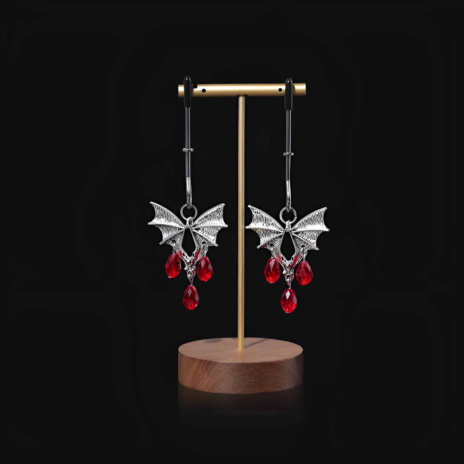 Silver bat-shaped nipple clamp with ruby gemstone and adjustable mechanism.