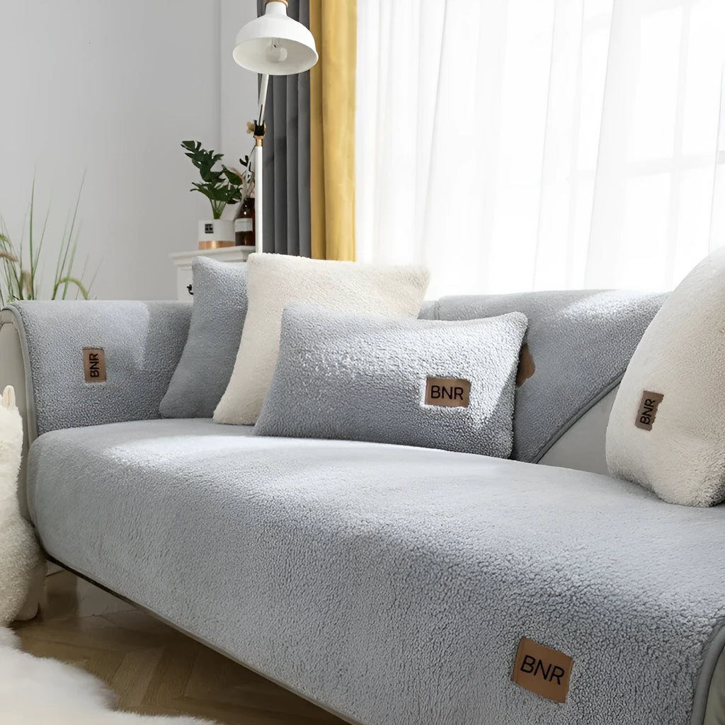 Lambswool machine-washable sofa cover in solid blue colour on a grey sofa