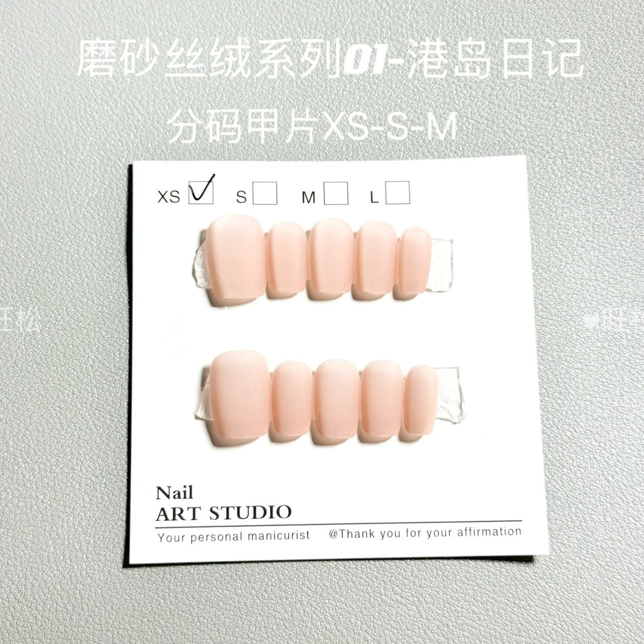 Set of frosted velvet Cat's Eye false nail wraps in short ladder sizes XS, S, and M on a display stand.