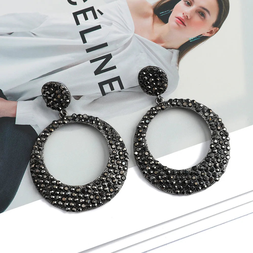 A pair of large colourful round pendant drop earrings with a cartoon style, made from metal alloy.