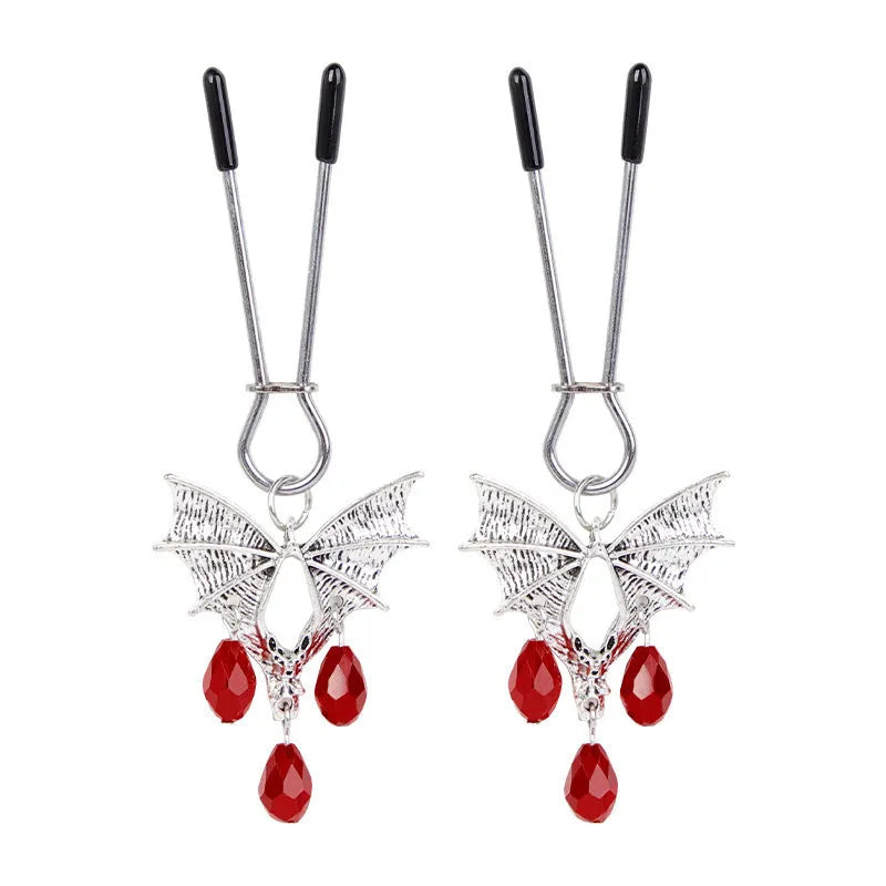 Silver bat-shaped nipple clamp with ruby gemstone and adjustable mechanism.
