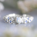 Peach-coloured women's heart-shaped ring with a detailed flower opal ocean design on its surface.