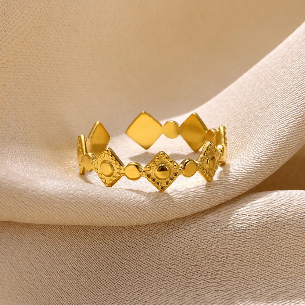 Gold diamond coloured titanium steel geometric women's ring on a plain background.