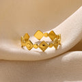 Gold diamond coloured titanium steel geometric women's ring on a plain background.
