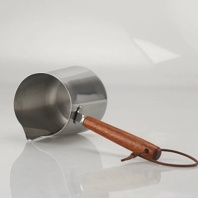Stainless steel milk frothing jug with volume scale and wooden handle in three size options.