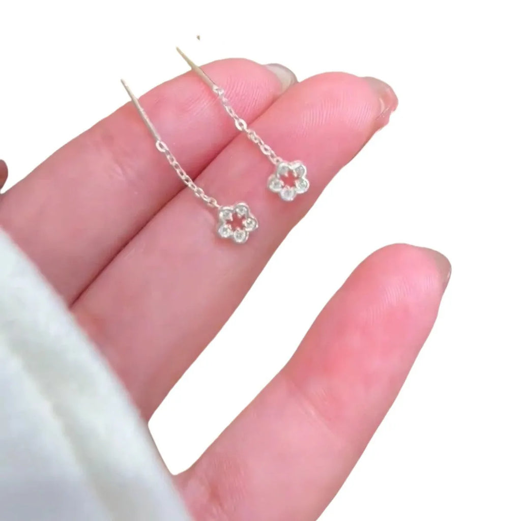 A pair of silver-coloured hollow flower drop earrings with detailed petals, shown against a plain background.