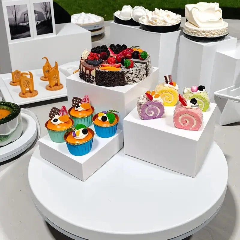 Set of six white geometric plastic cubes arranged as a tiered dessert display stand.