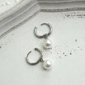 A pair of women's geometric alloy drop earrings with a round pearl centre and titanium steel post.