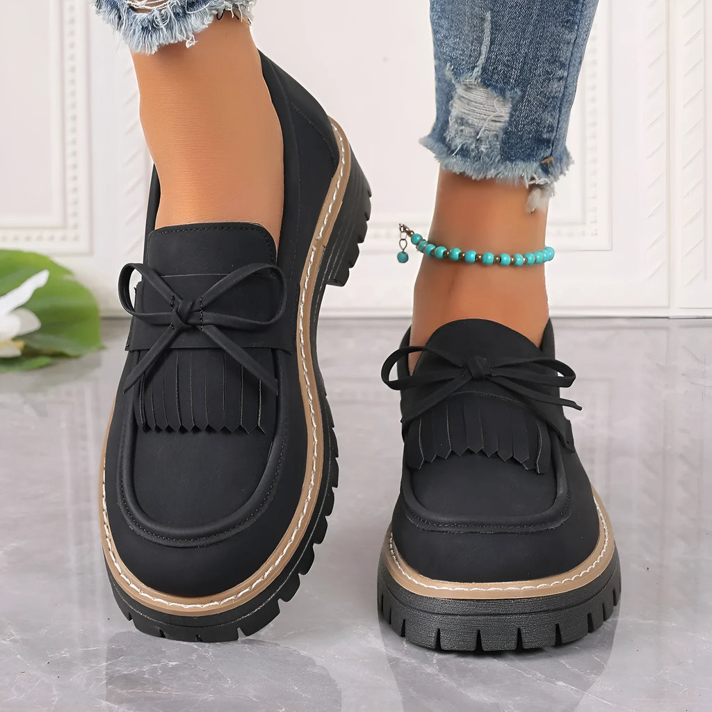 Plus size women's black loafers with a tassel and bow knot detail on the upper.