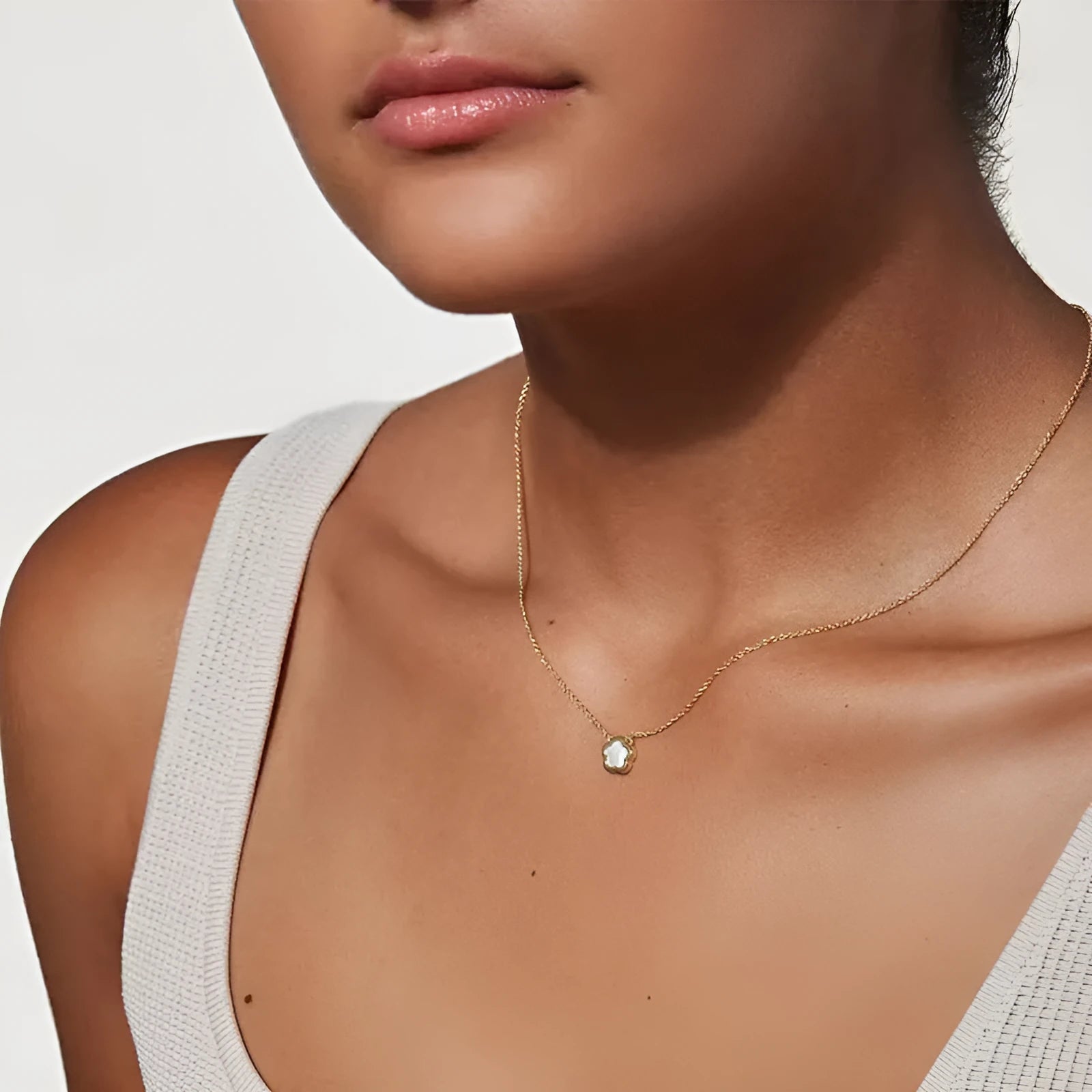 White mother-of-pearl shell flower necklace on a chain in silver or gold tone.