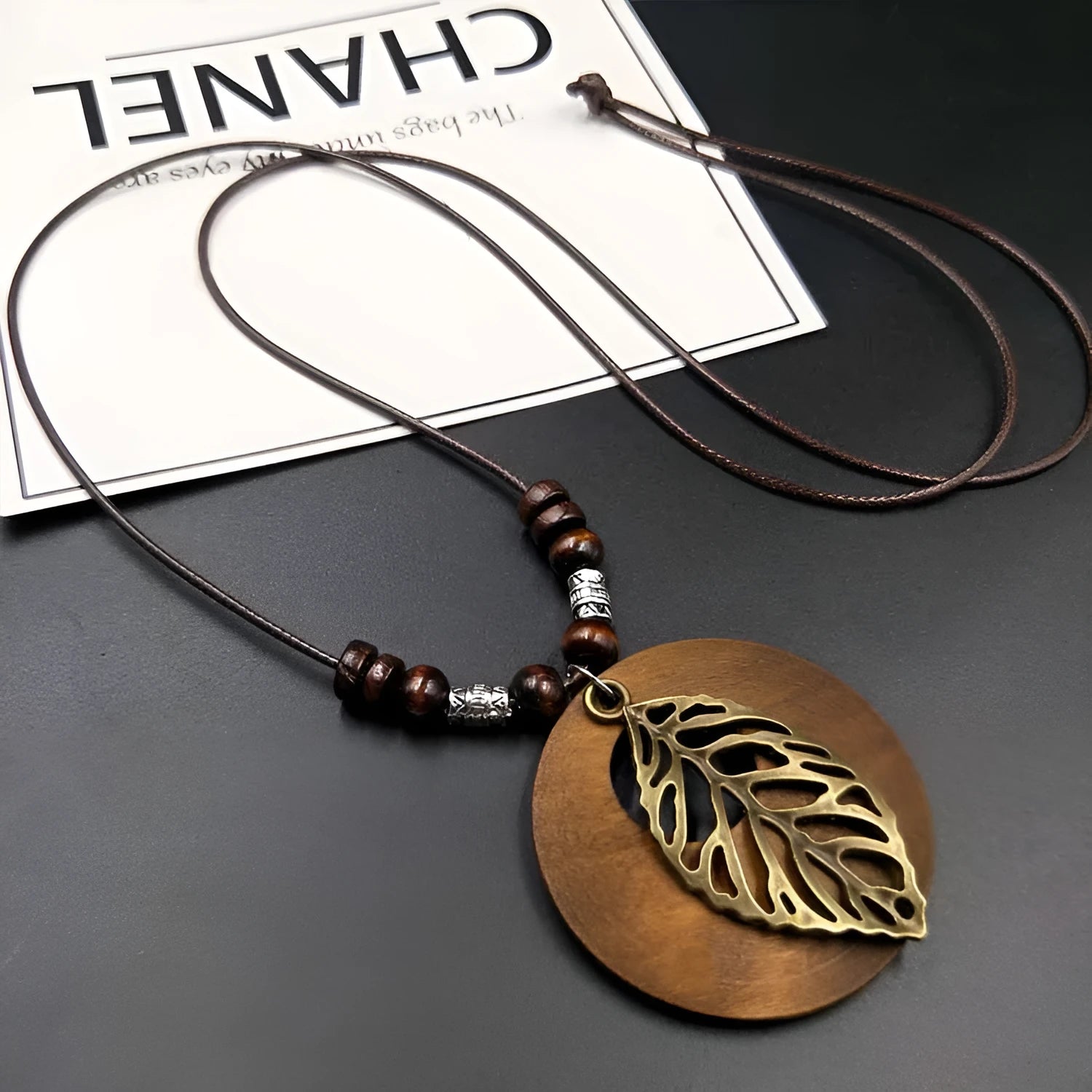 Vintage wooden leaf necklace on an adjustable beige linen cord, showing pendant detail.