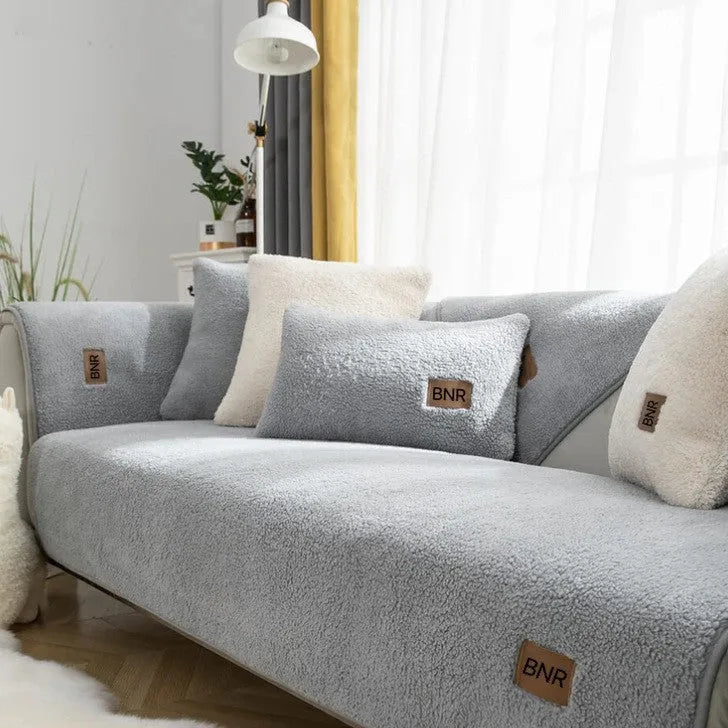 Lambswool machine-washable sofa cover in solid blue colour on a grey sofa