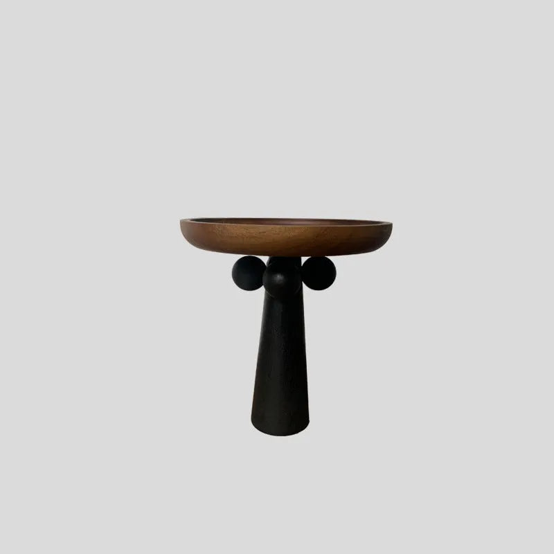 Round natural wooden tray with high legs holding a candle and perfume bottle on a table.