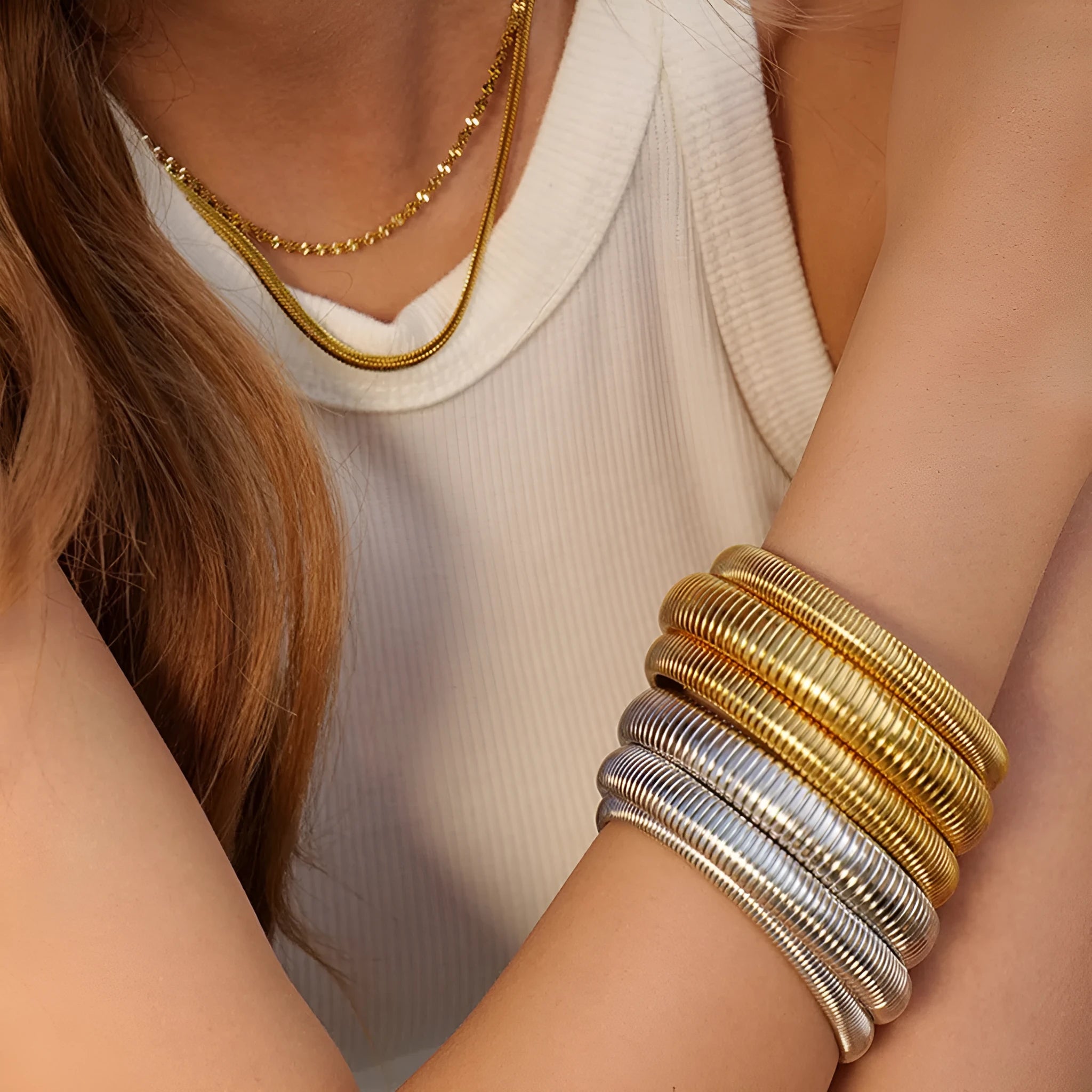 Close-up of a women's elastic titanium steel bracelet featuring a bold vertical stripe ring pattern in a gold tone finish.