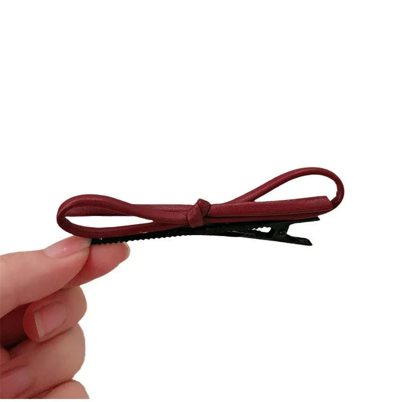 Wine red leather bow hair barrette on hair, showing single clip design
