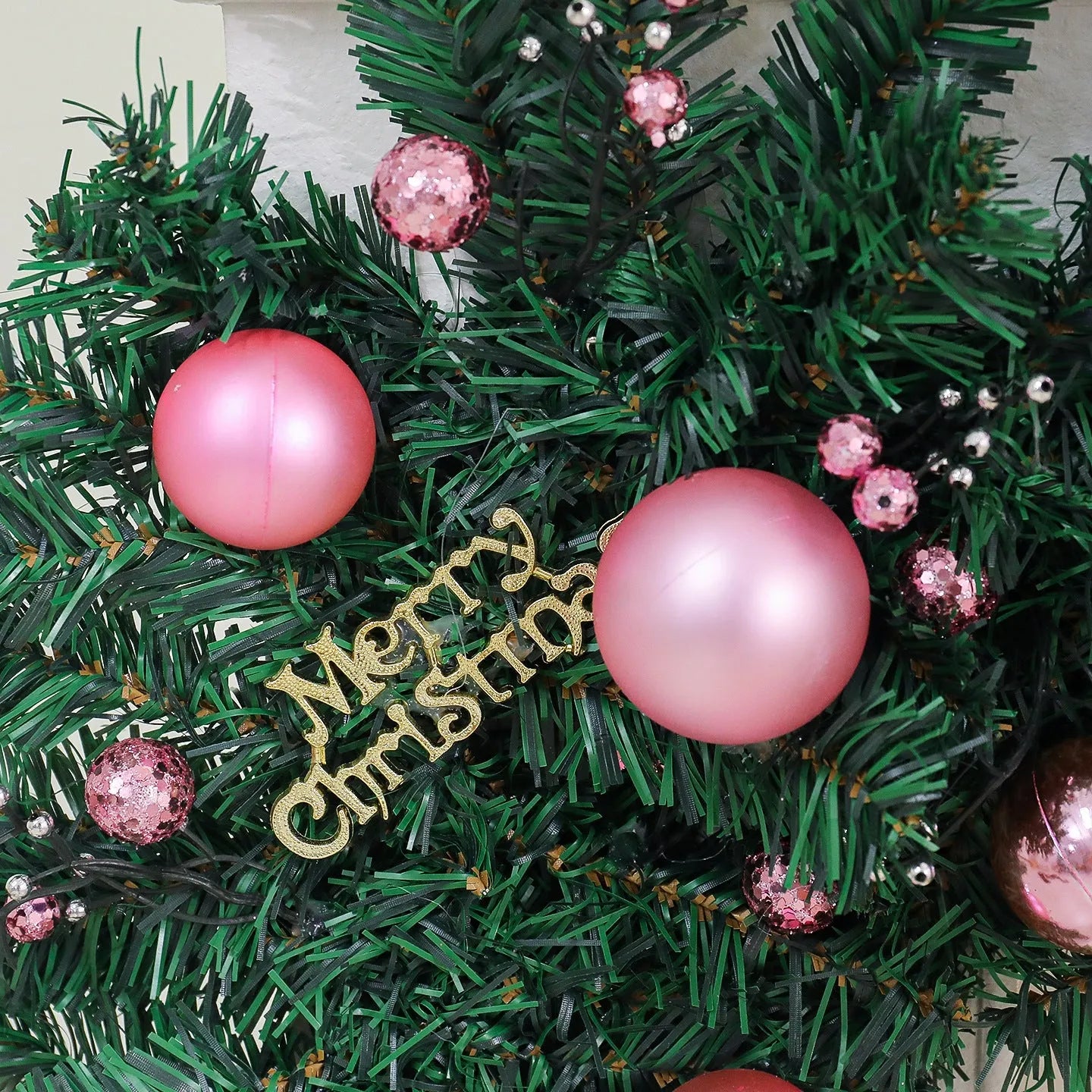 Long pink rattan Christmas garland with small fruit details and optional warm white lights draped on a mantle.