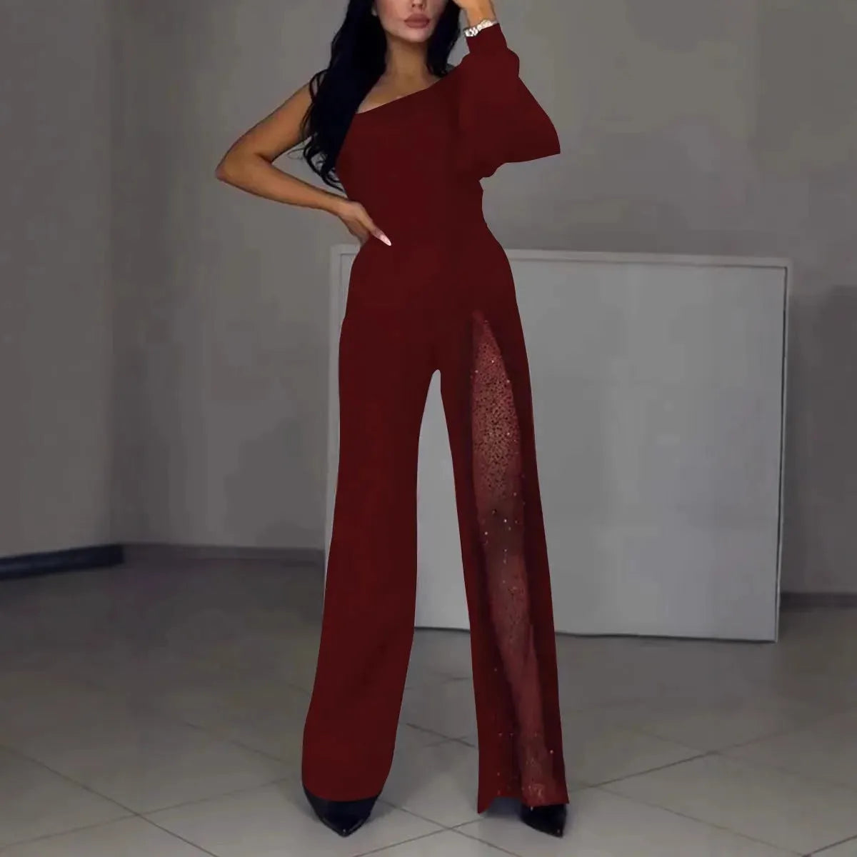 Black women's jumpsuit with one shoulder cut and high leg slit, made from polyester fabric.