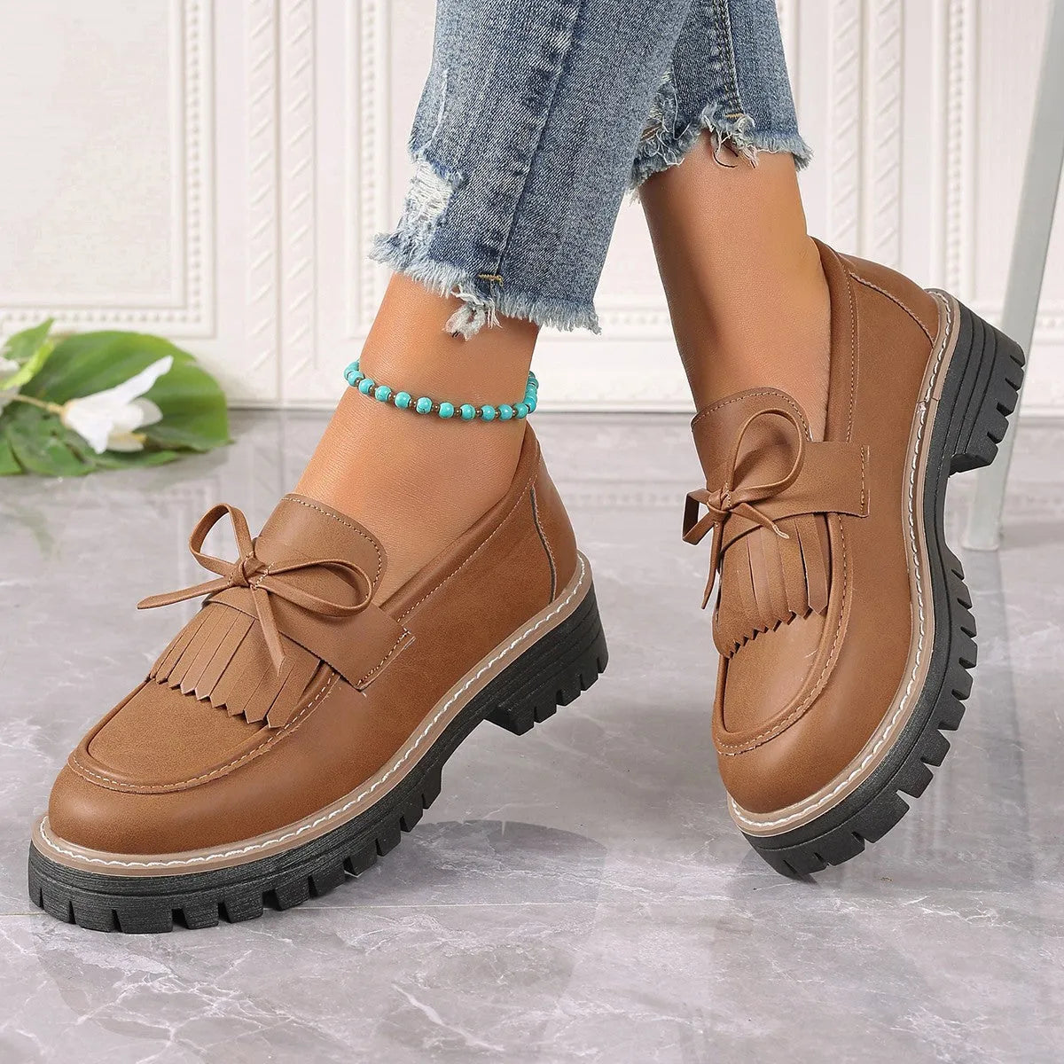 Plus size women's black loafers with a tassel and bow knot detail on the upper.