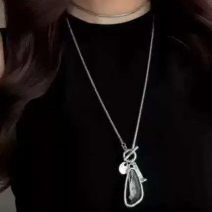 Long alloy sweater chain necklace with a geometric plaid pendant on a snake bones chain.