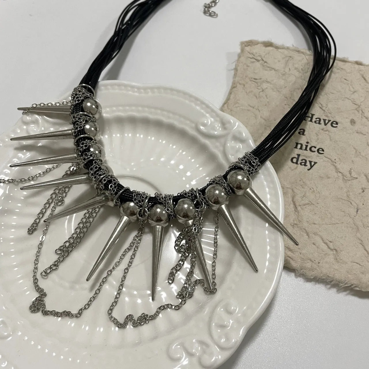 Women's casual leather necklace with round beads, a winding tassel, and decorative rivet details in an electroplated finish.