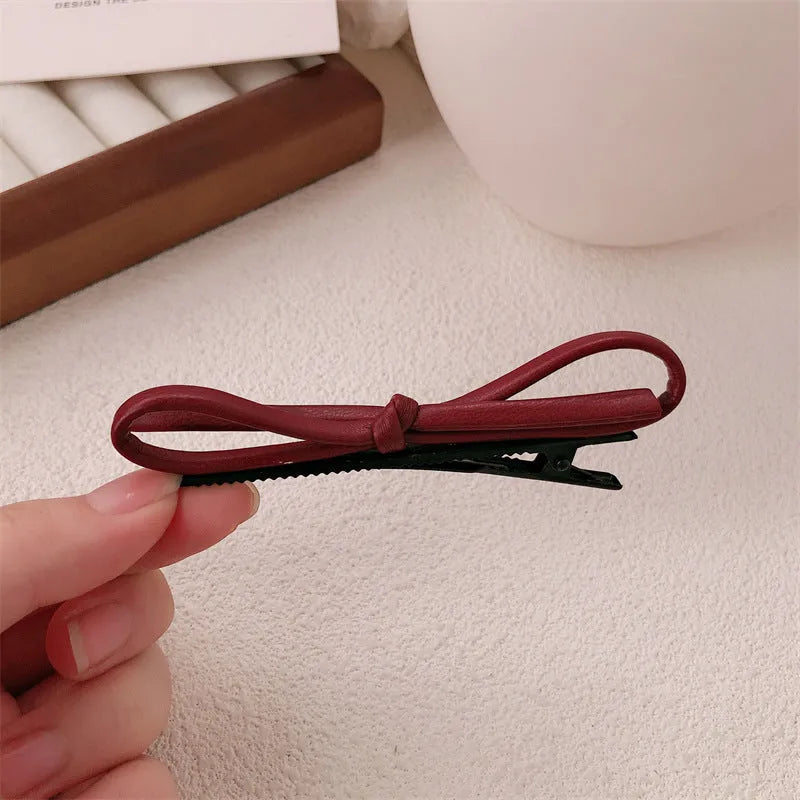 Wine red leather bow hair barrette on hair, showing single clip design