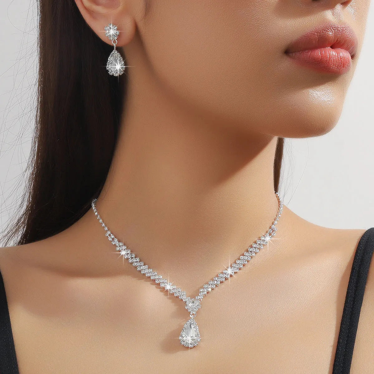 Women's blue claw chain necklace and drop rhinestone earrings from a matching jewellery set.
