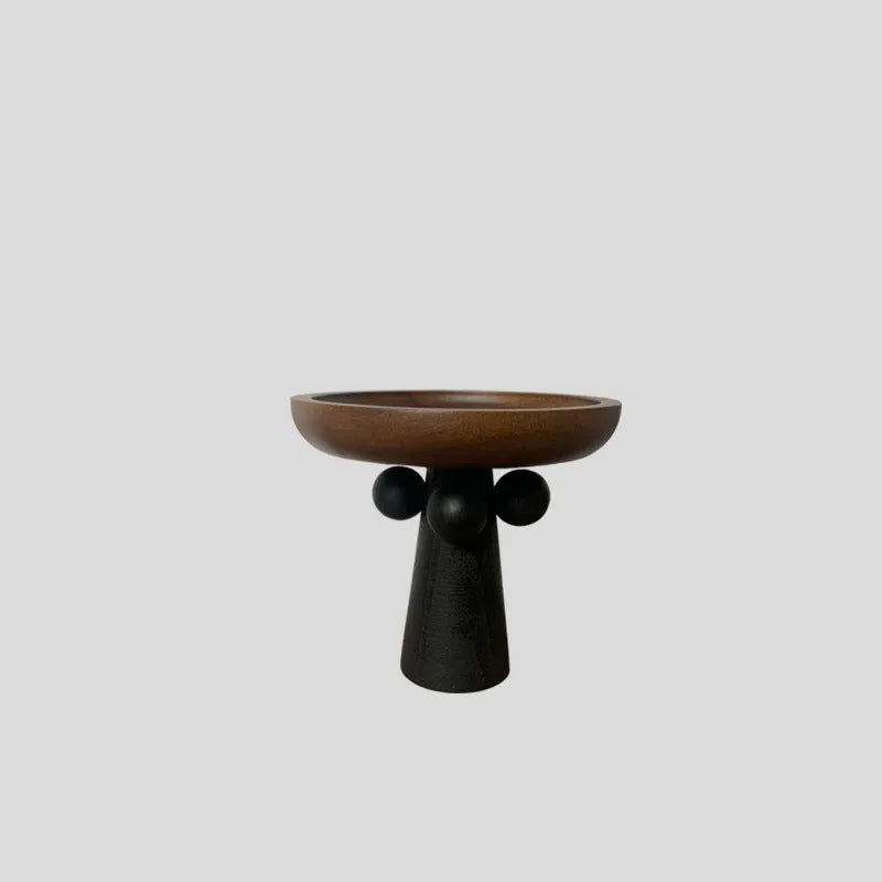 Round natural wooden tray with high legs holding a candle and perfume bottle on a table.