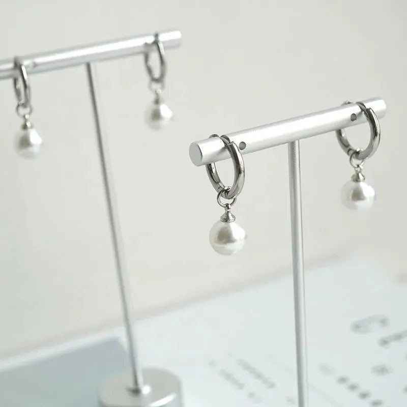 A pair of women's geometric alloy drop earrings with a round pearl centre and titanium steel post.