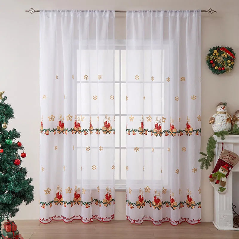 Pair of white Christmas curtains with embroidered red and green snowflake design, hung on a window.