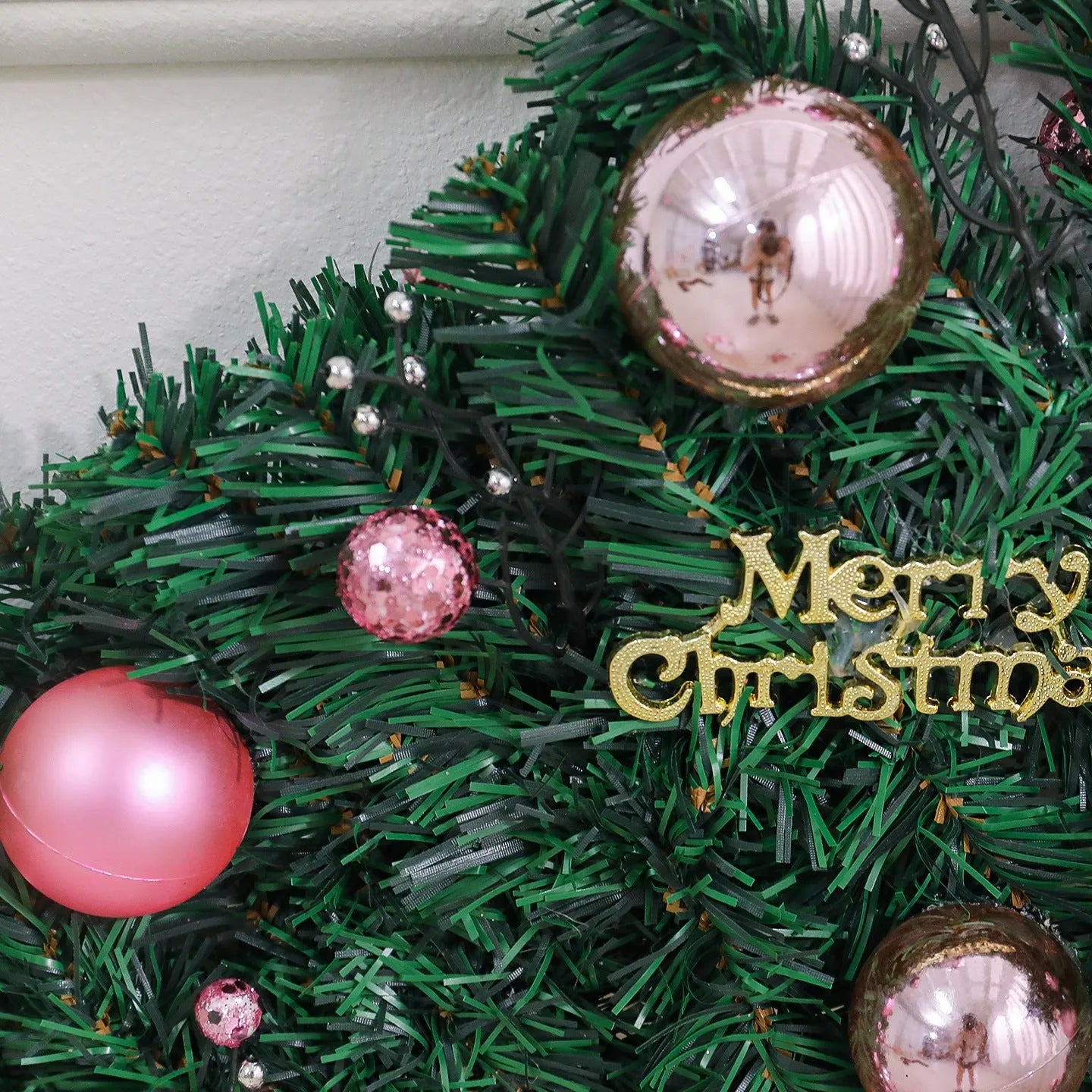 Long pink rattan Christmas garland with small fruit details and optional warm white lights draped on a mantle.
