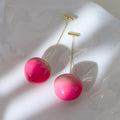 A pair of acrylic peach-shaped earrings with copper fittings, shown in small and large size options.
