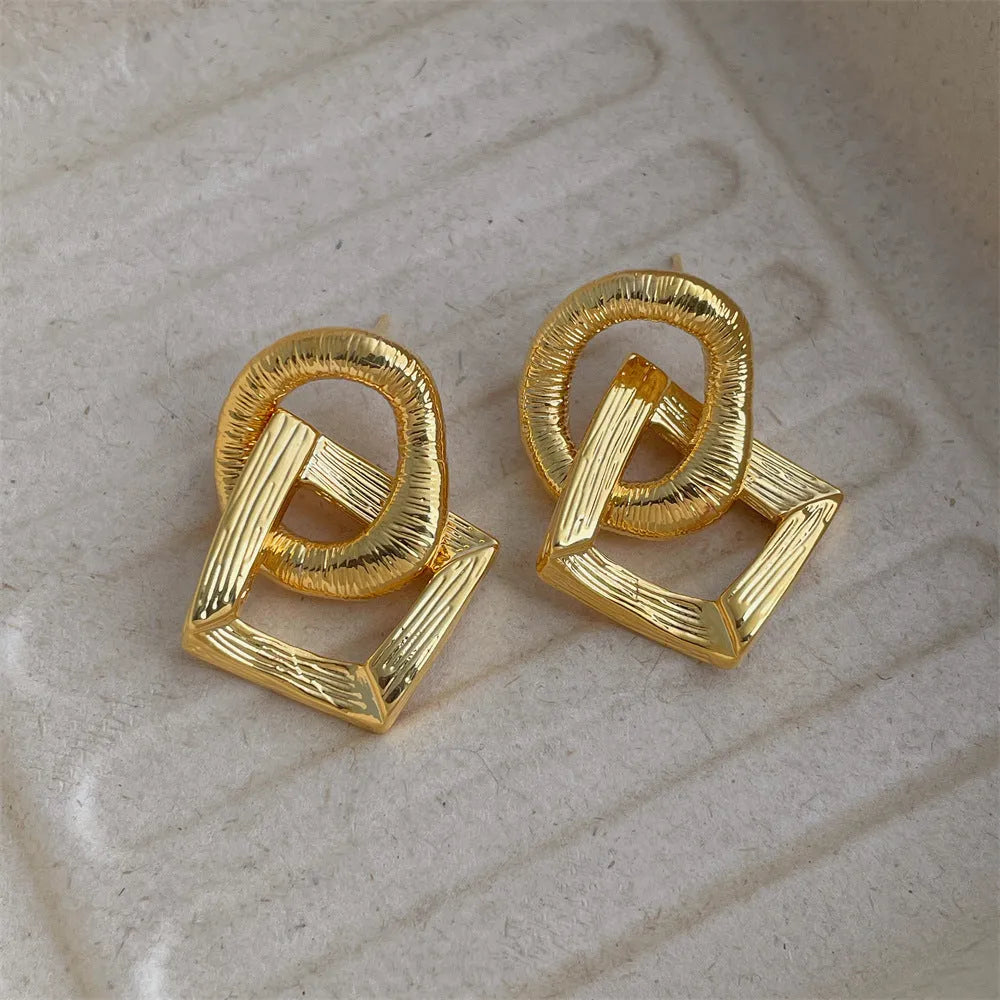 Retro geometric circle pendant earrings in gold or silver tone on a white background.