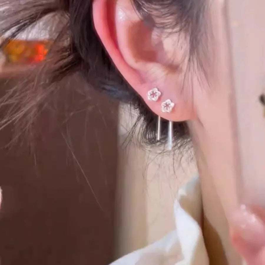 A pair of silver-coloured hollow flower drop earrings with detailed petals, shown against a plain background.