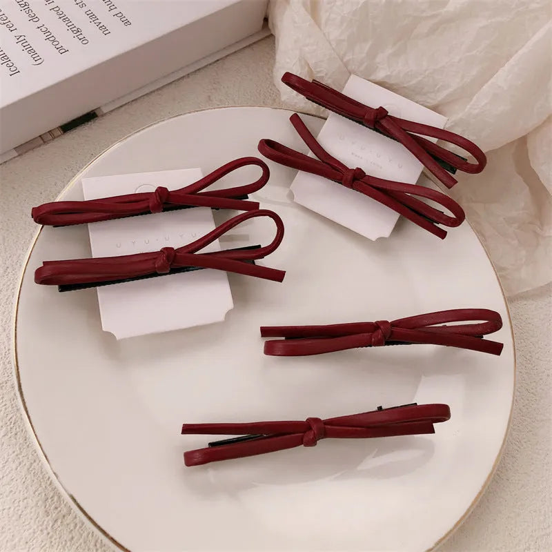 Wine red leather bow hair barrette on hair, showing single clip design